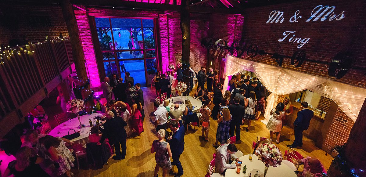 Wedding guests enjoy the evening wedding reception in the Mill Barn at Gaynes Park in Essex